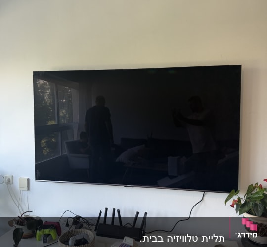 טלוויזיה תלויה על הקיר עם שולחן מתחתיה